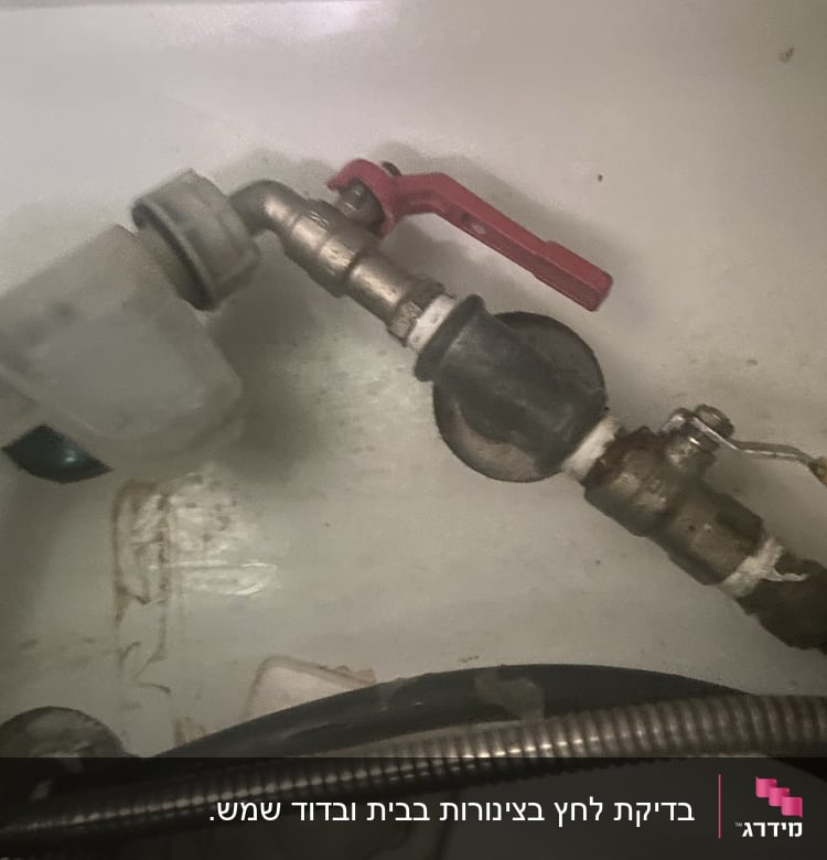 צינור עם ברז אדום וחיבורים מתכתיים
